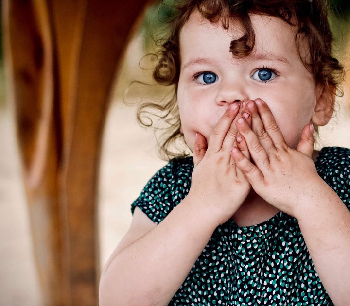 kleines Mädchen hält erschrocken die Hände vor ihren Mund